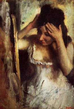 Kvinnan kammar sitt hår framför en spegel
