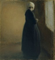 An old woman standing by a window