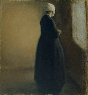 En gammal kvinna som står vid ett fönster